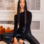 Woman in black outfit sitting on a couch in a stylish room.