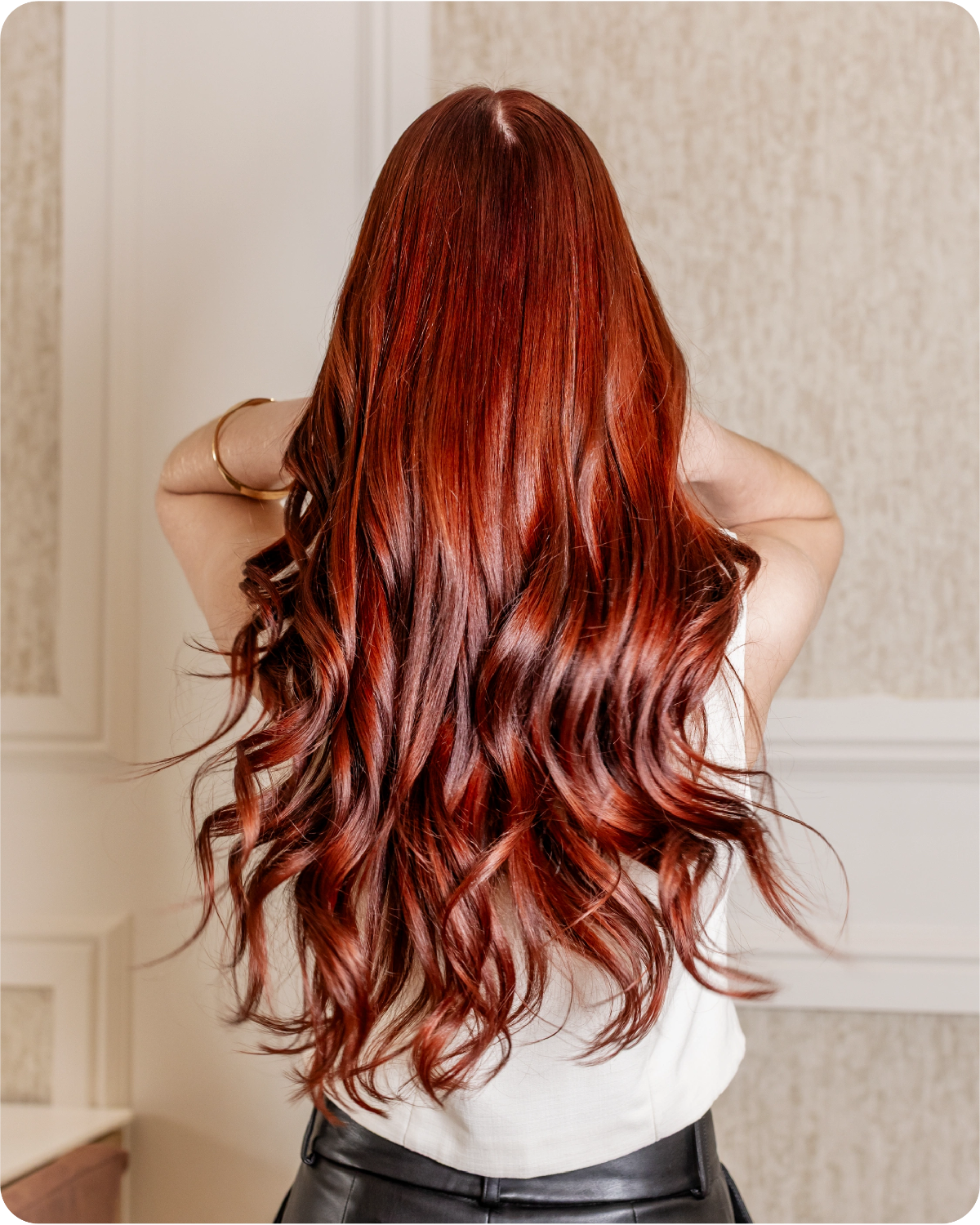 woman with back to camera, her red long hair is shinny and gorgeous as she uses kroma color 