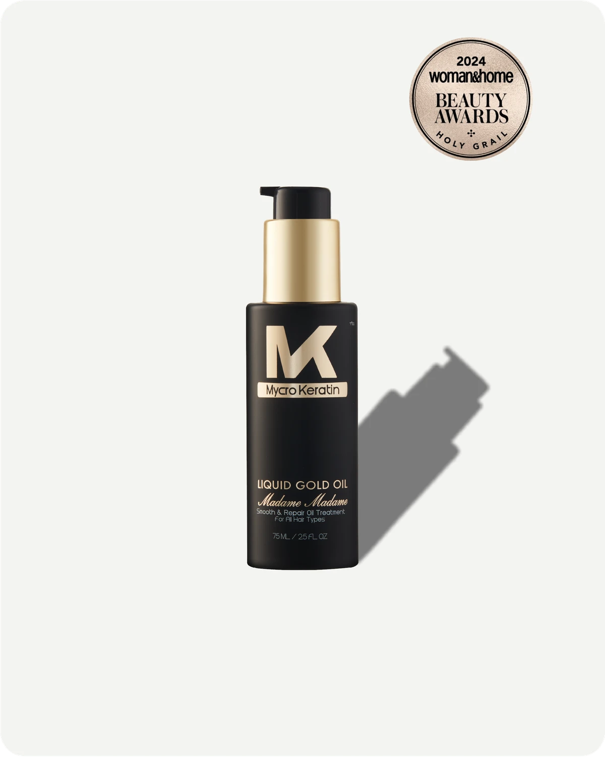 Black bottle of Madme Liquid Gold Oil with a gold cap on a white background, featuring an award badge.