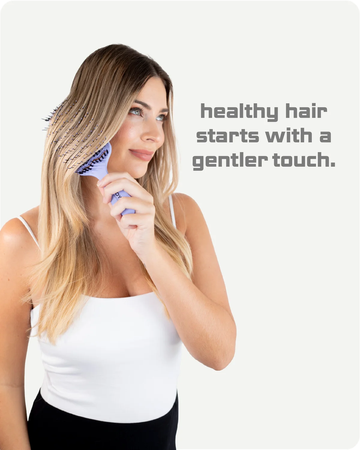 Woman using a hairbrush with text 'healthy hair starts with a gentler touch' on a white background