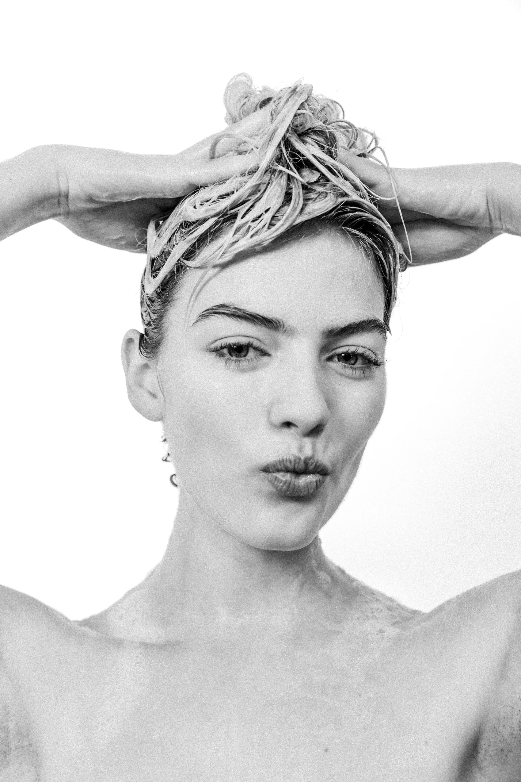 Black and white portrait of a woman with a headscarf blowing a kiss.