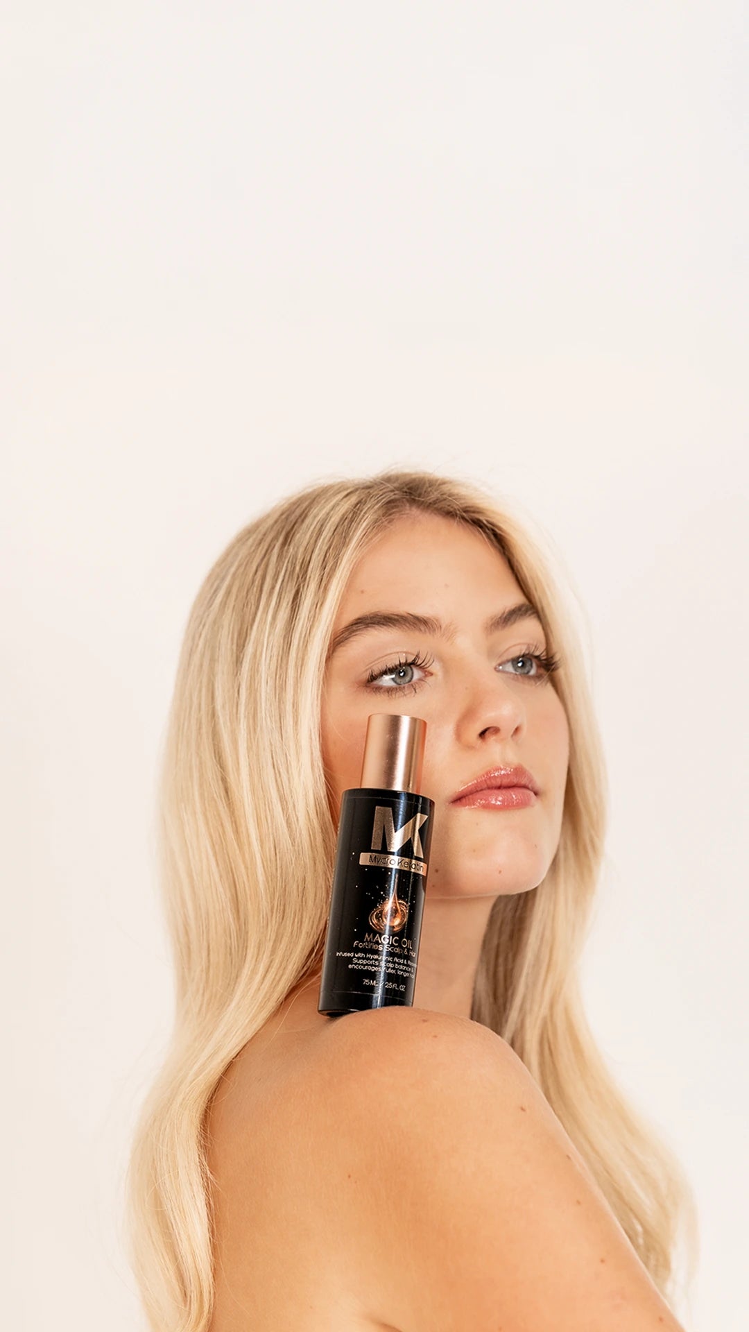 model with beautiful hair holding a bottle of mycro keratin magic oil 